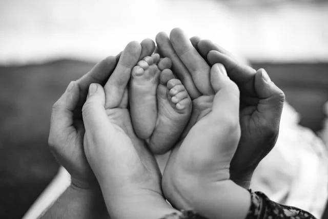 Hands of a family cradling a newborn's feet — the essence of care